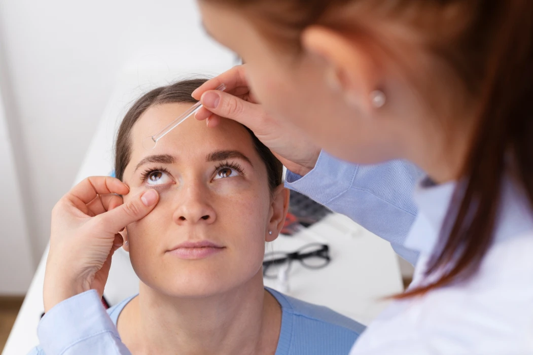A woman receiving an eye drop from a pharmacist for conjunctivitis