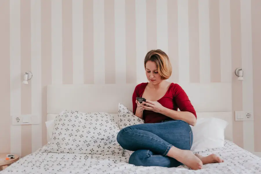 Beautiful woman browsing smartphone on bed